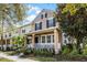 Charming two-story home featuring tan stucco, black shutters, and a welcoming front porch with white railings and manicured landscaping at 9228 Cardinal Meadow Trl, Orlando, FL 32827