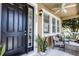 Inviting front porch with black door, decorative plants, seating and a ceiling fan, perfect for relaxing outdoors at 9228 Cardinal Meadow Trl, Orlando, FL 32827