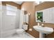 Well-lit bathroom features a white bathtub, toilet, sink, and a window for natural light at 12018 Radbourne St, Winter Garden, FL 34787