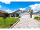 Charming single-story home features a well-manicured lawn, paver driveway, and a welcoming covered porch with seating at 127 Thorne Meadow Pass, Davenport, FL 33897