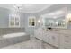 Bright bathroom with marble floors, white cabinets, double sinks, large tub, and plantation shutters at 12848 Jacob Grace Ct, Windermere, FL 34786