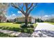 Well-manicured lawn with mature trees leading to a single-story home with a stone driveway and a three-car garage at 12848 Jacob Grace Ct, Windermere, FL 34786