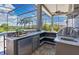 Covered outdoor kitchen with a built-in grill and bar seating, overlooking the pool and lush yard at 12848 Jacob Grace Ct, Windermere, FL 34786