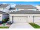 Neutral townhome exterior with a two-car garage, dark carriage lamps, and well-maintained landscaping at 13727 Bressler Aly, Windermere, FL 34786