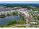 Aerial view of a mixed-use community with residential buildings, retail spaces, and a scenic lake at 14225 Southern Red Maple Dr, Orlando, FL 32828