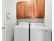 Laundry room with wood cabinets and a white washer and dryer at 14225 Southern Red Maple Dr, Orlando, FL 32828