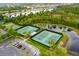 Aerial view of tennis courts next to parking area, surrounded by lush trees and a pond at 14225 Southern Red Maple Dr, Orlando, FL 32828
