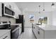 Well-lit kitchen featuring stainless steel appliances, white cabinets, pendant lights, and gray flooring at 16659 Sw 21St Avenue Rd, Ocala, FL 34473