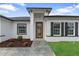 A modern home entrance with a unique wooden door, well-kept garden and black window shutters at 2480 Sw 147Th Lane Rd, Ocala, FL 34473