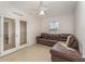 Bright living room has a brown leather sectional, ceiling fan, neutral tile flooring and access to another room through French doors at 322 Dagama Ct, Kissimmee, FL 34758