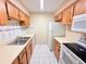 Galley kitchen featuring light wood cabinets, white appliances, and tile flooring at 4882 S Semoran Blvd # 1408, Orlando, FL 32822