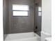 Modern bathroom featuring grey tile surround and a shower head above a white tub at 5443 Aeolus Way, Orlando, FL 32808