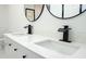 Modern bathroom with double vanity, featuring white countertops, black hardware, and sleek, black fixtures at 5443 Aeolus Way, Orlando, FL 32808