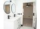 Bright bathroom featuring a double sink vanity with modern black fixtures, sleek round mirrors, and a doorway to the bedroom at 5443 Aeolus Way, Orlando, FL 32808