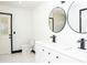 Bright bathroom featuring a double sink vanity with modern black fixtures, sleek round mirrors, and white marble floors at 5443 Aeolus Way, Orlando, FL 32808