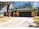 Charming single-story home featuring a two-car garage and well-maintained front yard with mature trees at 5443 Aeolus Way, Orlando, FL 32808