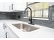 Kitchen featuring modern white cabinetry, gray subway tile backsplash, stainless sink and sleek black faucet at 5443 Aeolus Way, Orlando, FL 32808