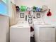 Bright laundry area with neatly arranged cleaning supplies, shelving, and white front load washer and dryer at 6404 Pine Fork Aly, St Cloud, FL 34771