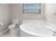 Bright bathroom featuring large garden tub and toilet under a window with blinds at 735 Deerfoot Rd, Deland, FL 32720