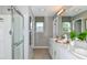 Neutral bathroom featuring double vanity, sleek lighting, framed mirrors, and a glass-enclosed shower at 7351 Capstone Dr, Groveland, FL 34736