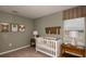 Cozy Bedroom featuring a white crib, wooden furniture, neutral walls, and cute animal art prints at 7355 Capstone Dr, Groveland, FL 34736