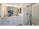 Bright bathroom featuring double vanity sinks, a large mirror, a glass-enclosed shower, and neutral decor at 7384 Capstone Dr, Groveland, FL 34736