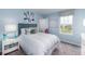 Cozy blue bedroom with striped bedding, soft pillows, side table, and a window overlooking the backyard at 7404 Capstone Dr, Groveland, FL 34736