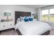 Bright main bedroom featuring a tufted headboard, bedside tables, lamps, and a large window with natural light at 7404 Capstone Dr, Groveland, FL 34736