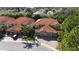 Aerial view of three homes in a residential neighborhood with mature trees and clay tile roofs at 8950 Della Scala Cir, Orlando, FL 32836