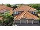 Aerial view of a home featuring a clay tile roof, three car garage, and manicured landscaping at 8950 Della Scala Cir, Orlando, FL 32836