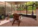 Screened-in patio area with brick flooring, wood furniture, and ample natural light from the surrounding greenery at 8950 Della Scala Cir, Orlando, FL 32836