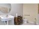 Well-lit bathroom with a pedestal sink, round mirror, wooden cabinet, and a toilet with accessibility bars at 907 Princess Sabal Pt, Haines City, FL 33844