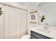 Clean bathroom with a shower featuring a neutral curtain, stylish wall art and blue vanity cabinet at 913 Sabal Breeze Ln, Apopka, FL 32703