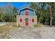 View of unique two story home with blue and tan exterior, red doors and surrounding greenery at 10031 Union Park Dr, Orlando, FL 32817