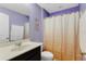 Compact bathroom featuring a single sink vanity, toilet, and shower with a neutral-toned curtain at 10566 Green Ivy Ln, Orlando, FL 32832