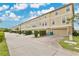 Street view showcasing townhome exteriors with front garages, driveways, manicured landscaping, and vibrant blue sky at 10566 Green Ivy Ln, Orlando, FL 32832