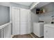 Upstairs laundry room equipped with modern washer, dryer, storage shelves, and bi-fold doors at 10566 Green Ivy Ln, Orlando, FL 32832