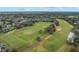 Expansive aerial view showing a well-maintained golf course surrounded by green trees and a residential community at 1094 Red Maple Way, New Smyrna Beach, FL 32168