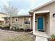 Home exterior showcasing a well-manicured front yard, a bright blue front door, and covered porch at 1197 Village Forest Pl, Winter Park, FL 32792