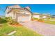 Paver driveway and a two-car garage with landscaped front yard in a suburban neighborhood at 125 Links Terrace Blvd, Daytona Beach, FL 32124