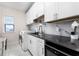 Modern laundry room with white cabinets, marble backsplash, black countertops and stainless-steel appliances at 1298 Patterson Ter, Lake Mary, FL 32746