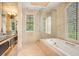 Spa-like bathroom with a soaking tub, glass-enclosed shower, double sinks, and neutral tile at 1400 Alabama Dr, Winter Park, FL 32789