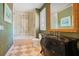 Elegant bathroom featuring a walk-in shower, patterned tile, and a vintage-style vanity with a gold-framed mirror at 1400 Alabama Dr, Winter Park, FL 32789