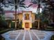 Elegant two-story home with manicured landscaping and a grand entrance, framed by mature palm trees and decorative driveway at 1400 Alabama Dr, Winter Park, FL 32789