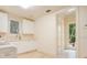 Bright laundry room with a white washer, light beige tile floor, white cabinets, and a door to the yard at 1400 Alabama Dr, Winter Park, FL 32789