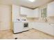 Bright laundry room with a white washer and dryer, light beige tile floor, white cabinets, and a window at 1400 Alabama Dr, Winter Park, FL 32789