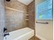 Bathroom with a bathtub and brown tiling, lit by a bright window at 1609 River Birch Ave, Oviedo, FL 32765