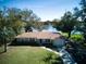 Aerial view of a tan house with front lawn, driveway, and backyard with lake access at 2055 Jessamine Ct, Deltona, FL 32738