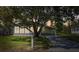 Dusk view of a charming single-story home featuring a well-maintained front yard, shade tree, and covered carport at 2706 Cranmoor Dr, Kissimmee, FL 34758