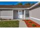 Close up front entrance with covered porch, landscaped flower beds and well kept lawn at 2740 Courtland Blvd, Deltona, FL 32738